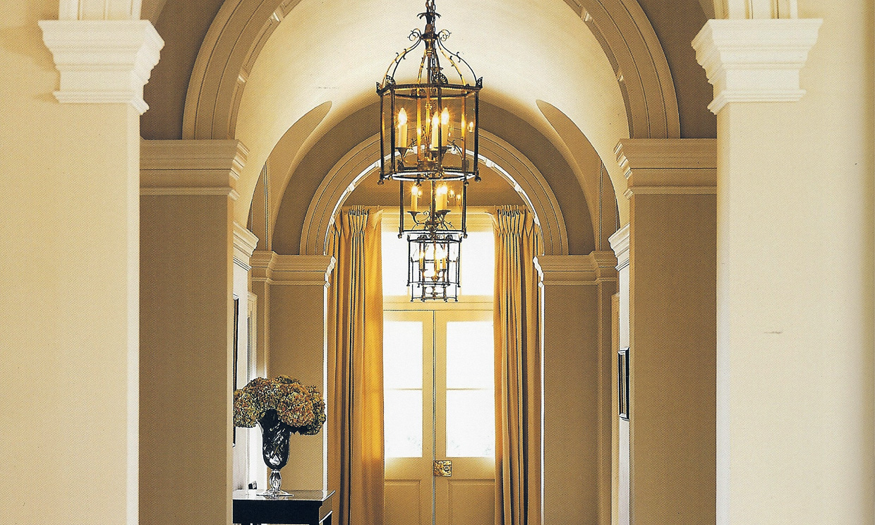 Elegant hallway with chandelier and arched doorway.