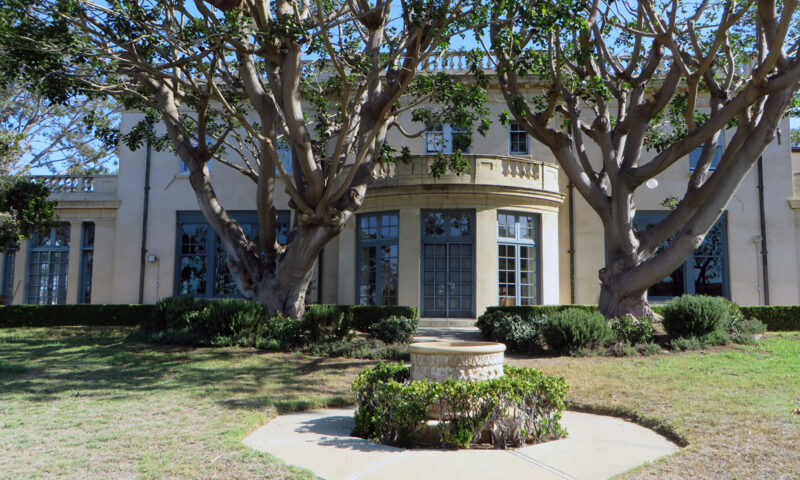 Large white house with a trees and fountain.