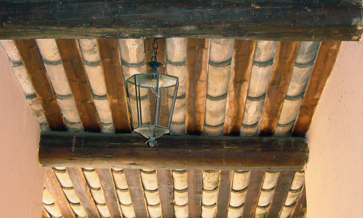 Ceiling with hanging lantern and wooden beams.